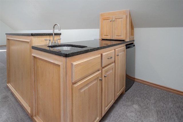 kitchen with a sink, dark carpet, light brown cabinetry, and dark stone countertops