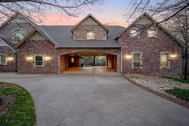 view of front of home with driveway, roof with shingles, and brick siding