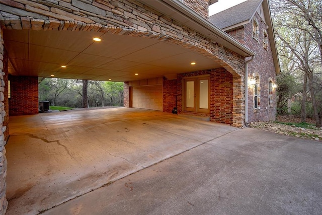 garage featuring a carport, driveway, and central AC unit