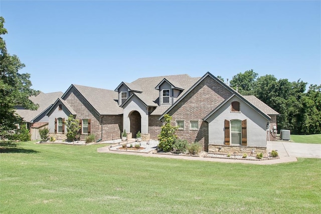 5625 Courtland Ln, Choctaw, OK 73020 - view of front facade with central AC unit, a front yard, stone siding, and brick siding