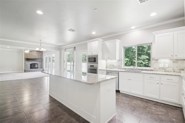 5625 Courtland Ln, Choctaw, OK 73020 - kitchen with appliances with stainless steel finishes, plenty of natural light, a center island, decorative backsplash, and ornamental molding