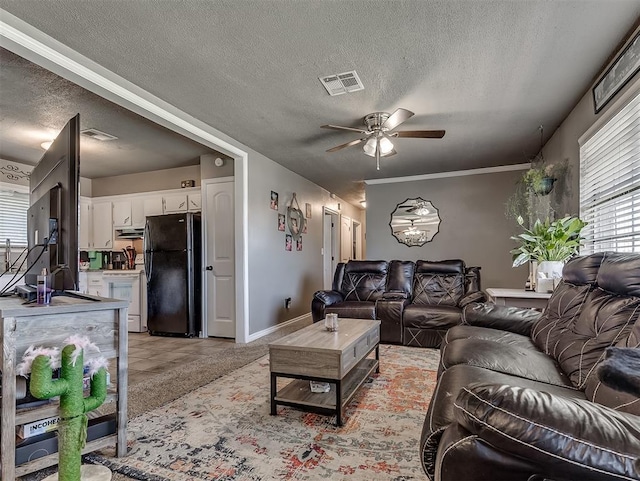 717 SW 4th Pl, Moore, OK 73160 - living room featuring a textured ceiling, a ceiling fan, and baseboards