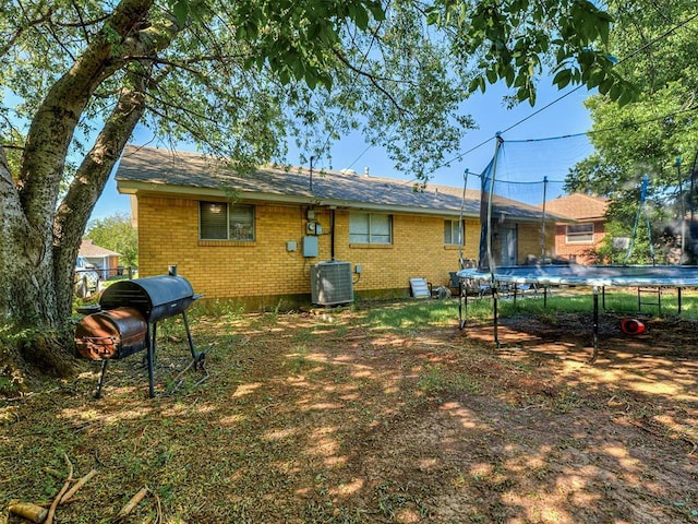 717 SW 4th Pl, Moore, OK 73160 - back of property featuring a trampoline, brick siding, and central AC unit