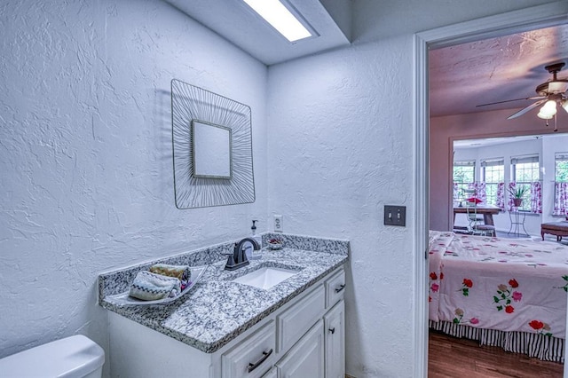 3517 Brookford Dr, Norman, OK 73072 - bathroom with a textured wall, wood finished floors, toilet, vanity, and ceiling fan
