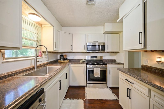308 E Highland St, Hugo, OK 74743 - kitchen with stainless steel appliances, a sink, dark wood-style floors, a textured ceiling, and white cabinets