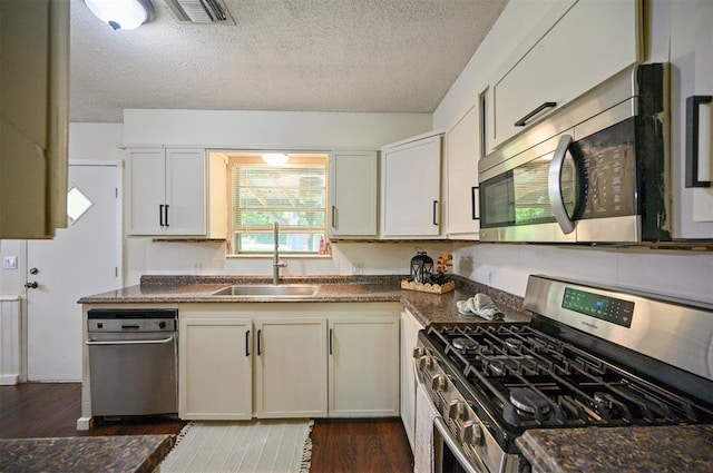 308 E Highland St, Hugo, OK 74743 - kitchen featuring appliances with stainless steel finishes, a sink, dark countertops, and a textured ceiling