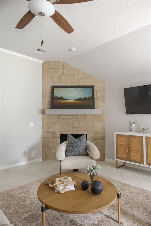 6812 NW 149th St, Oklahoma City, OK 73142 - living room with a fireplace, ceiling fan, ornamental molding, lofted ceiling, and a textured ceiling