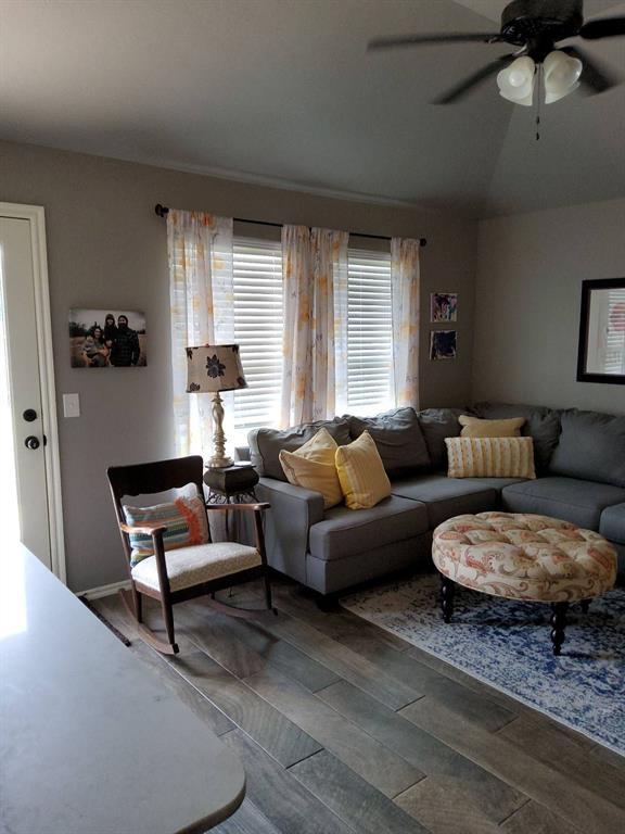 living area featuring ceiling fan, wood finished floors, and lofted ceiling