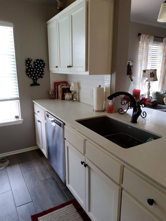 kitchen with dishwasher, a sink, light countertops, and white cabinets