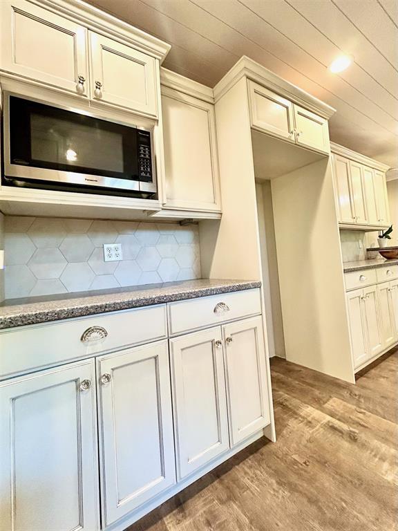 4008 Creekwood, Edmond, OK 73025 - kitchen with stainless steel microwave, tasteful backsplash, light wood finished floors, light stone counters, and wooden ceiling