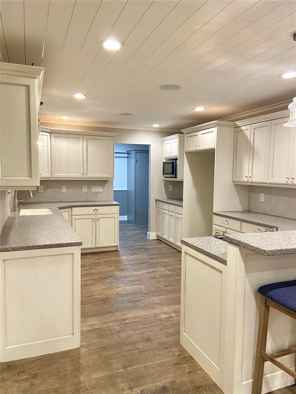 4008 Creekwood, Edmond, OK 73025 - kitchen featuring stainless steel microwave, recessed lighting, light stone countertops, a sink, and dark wood-style flooring