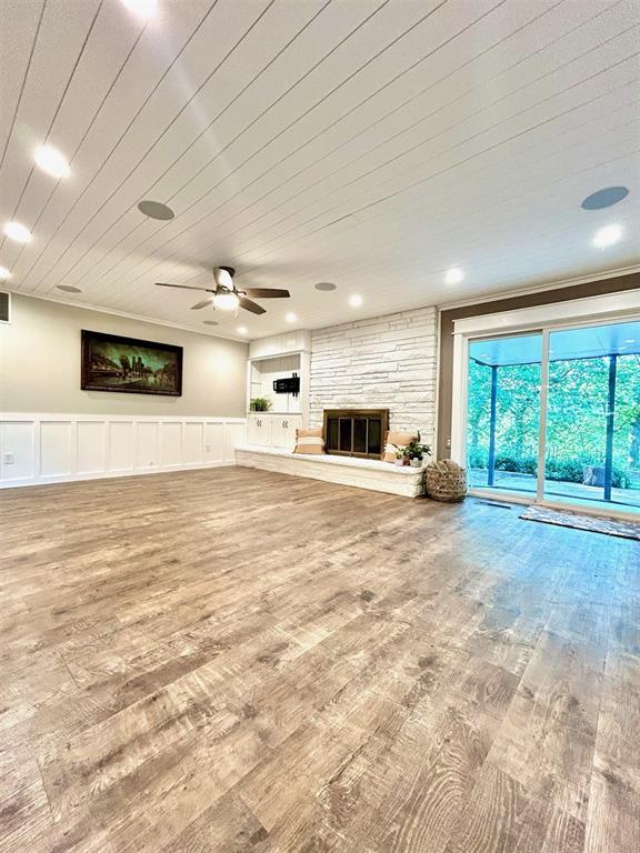 4008 Creekwood, Edmond, OK 73025 - unfurnished living room featuring wood finished floors, a fireplace, and a ceiling fan
