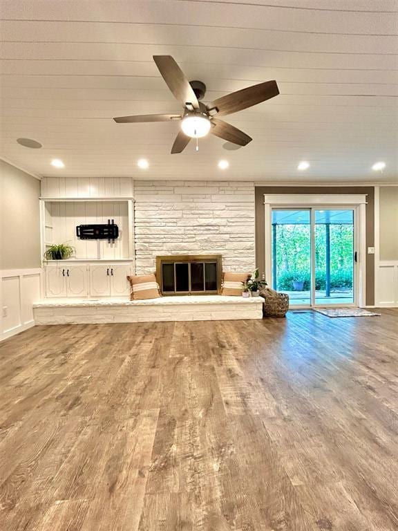 4008 Creekwood, Edmond, OK 73025 - unfurnished living room with a decorative wall, a ceiling fan, wood finished floors, wainscoting, and a fireplace