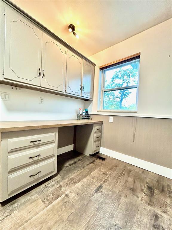 4008 Creekwood, Edmond, OK 73025 - unfurnished office featuring built in desk, light wood-style flooring, and baseboards
