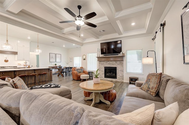 living room featuring a barn door, crown molding, wood finished floors, coffered ceiling, and beam ceiling