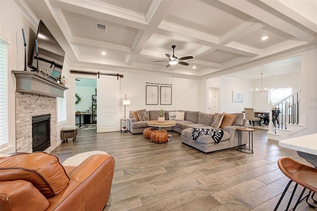 living area with a barn door, a chandelier, ceiling fan, coffered ceiling, and beamed ceiling
