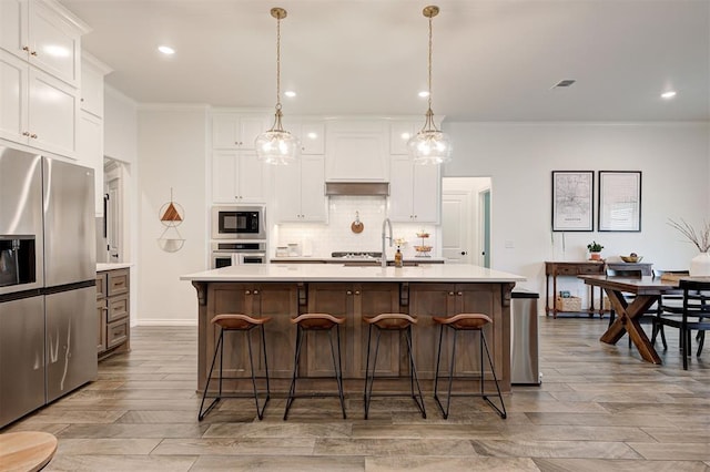 kitchen with appliances with stainless steel finishes, custom range hood, light countertops, crown molding, and tasteful backsplash