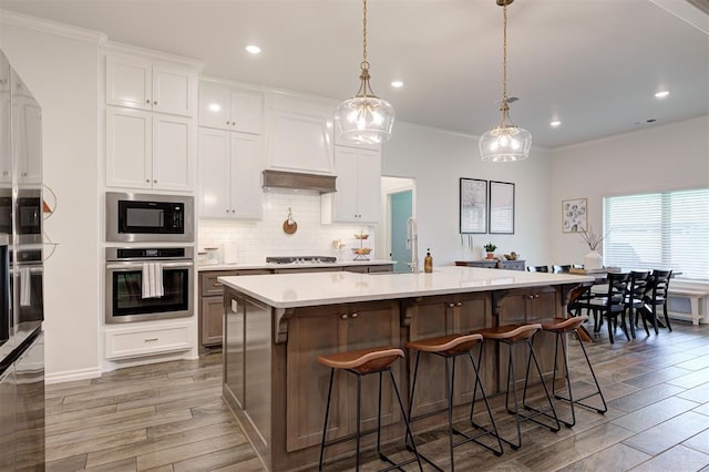 kitchen with stainless steel oven, wood finished floors, light countertops, a sink, and gas cooktop