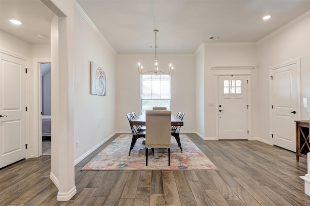 dining room with a chandelier, ornamental molding, plenty of natural light, wood finished floors, and baseboards