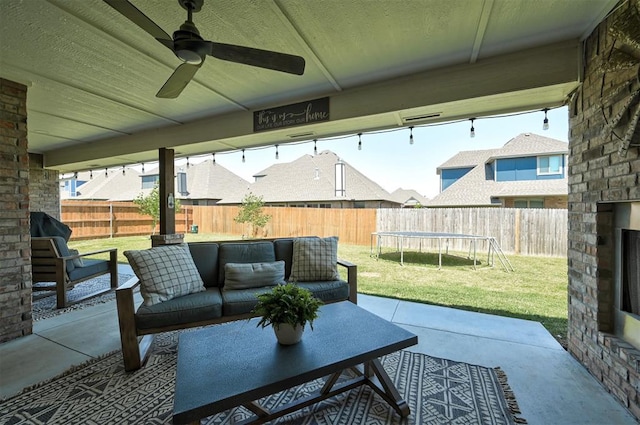 view of patio / terrace featuring a trampoline, an outdoor living space with a fireplace, and ceiling fan