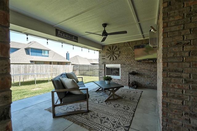 view of patio / terrace featuring an outdoor brick fireplace, a fenced backyard, and a ceiling fan