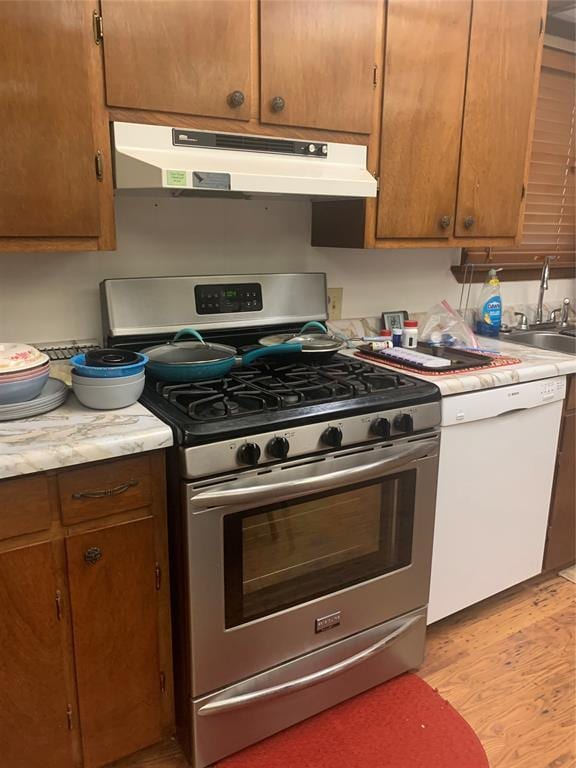 845 N Washington Ave, Mountain View, OK 73062 - kitchen with gas range, under cabinet range hood, dishwasher, a sink, and light countertops