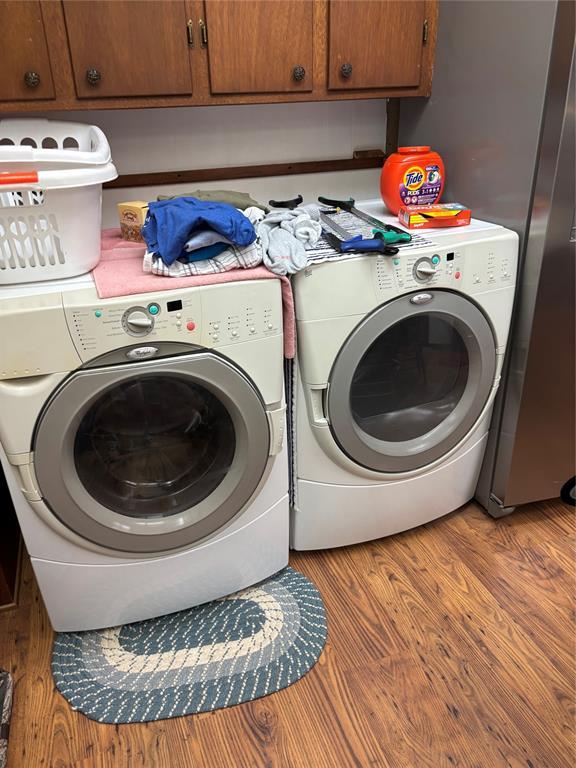 845 N Washington Ave, Mountain View, OK 73062 - laundry room featuring washing machine and dryer, cabinet space, and wood finished floors