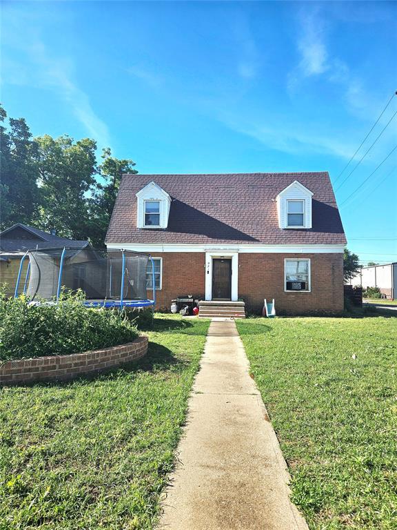 921 E Walnut St, Altus, OK 73521 - cape cod house featuring a trampoline, a front lawn, and brick siding