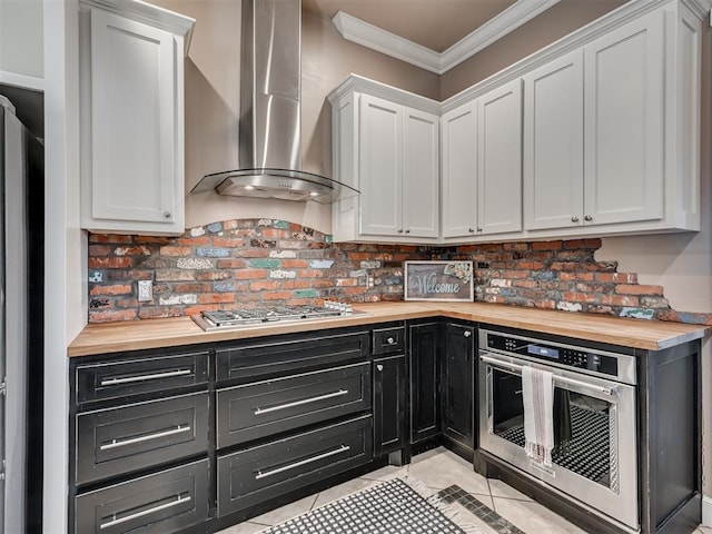 24051 Hester Cir, Washington, OK 73093 - kitchen with butcher block countertops, wall chimney range hood, dark cabinets, white cabinetry, and crown molding