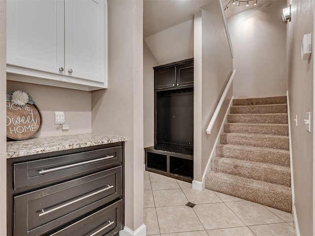 24051 Hester Cir, Washington, OK 73093 - kitchen with light tile patterned floors, light stone countertops, white cabinets, baseboards, and vaulted ceiling