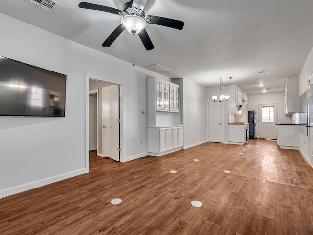 24051 Hester Cir, Washington, OK 73093 - unfurnished living room with a ceiling fan, light wood-style floors, baseboards, and a chandelier