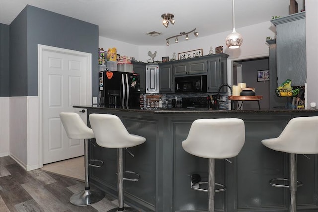 717 Vickery Ave, Yukon, OK 73099 - kitchen with black appliances, a breakfast bar area, wood finished floors, and decorative backsplash