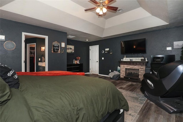 717 Vickery Ave, Yukon, OK 73099 - bedroom featuring wood finished floors, a tray ceiling, a fireplace, and baseboards