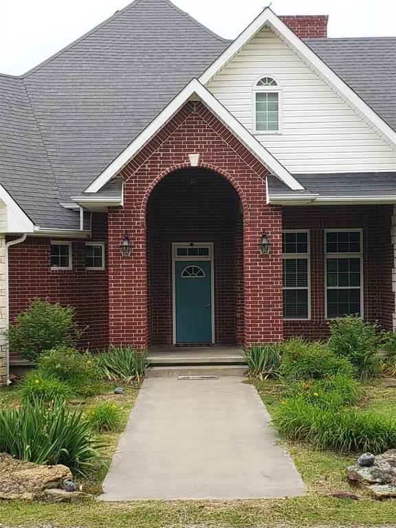 7336 E 136th Rd, Holdenville, OK 74848 - doorway to property featuring brick siding and a shingled roof
