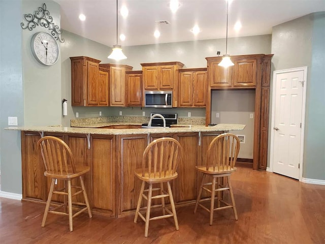 7336 E 136th Rd, Holdenville, OK 74848 - kitchen with stainless steel microwave, brown cabinets, baseboards, and light stone countertops