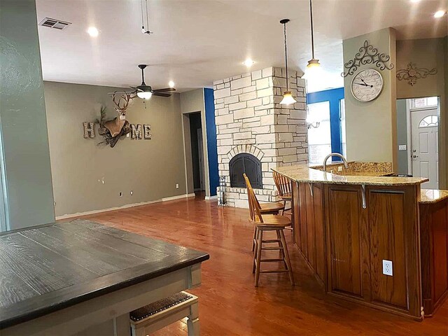 7336 E 136th Rd, Holdenville, OK 74848 - kitchen with ceiling fan, wood finished floors, a kitchen bar, light stone counters, and hanging light fixtures