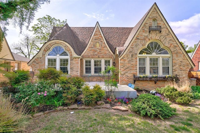 3104 NW 21st St, Oklahoma City, OK 73107 - english style home featuring brick siding, a shingled roof, and a patio
