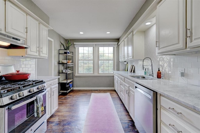 3104 NW 21st St, Oklahoma City, OK 73107 - kitchen with appliances with stainless steel finishes, ventilation hood, dark wood finished floors, white cabinets, and decorative backsplash