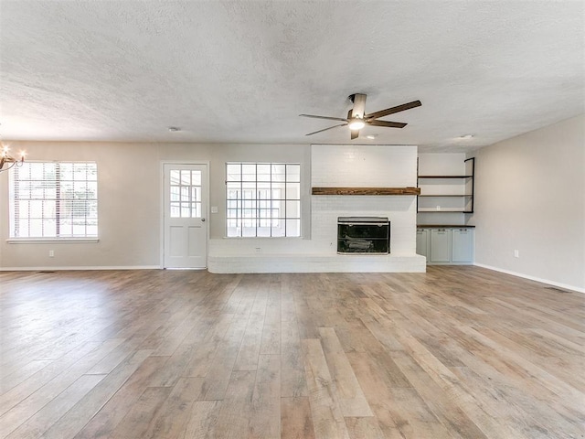 1400 Brookhaven Dr, Edmond, OK 73034 - unfurnished living room featuring a textured ceiling, ceiling fan, light wood finished floors, a chandelier, and baseboards