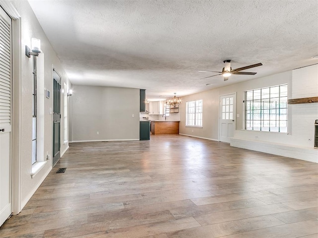 1400 Brookhaven Dr, Edmond, OK 73034 - unfurnished living room with a textured ceiling, a chandelier, ceiling fan, wood finished floors, and baseboards