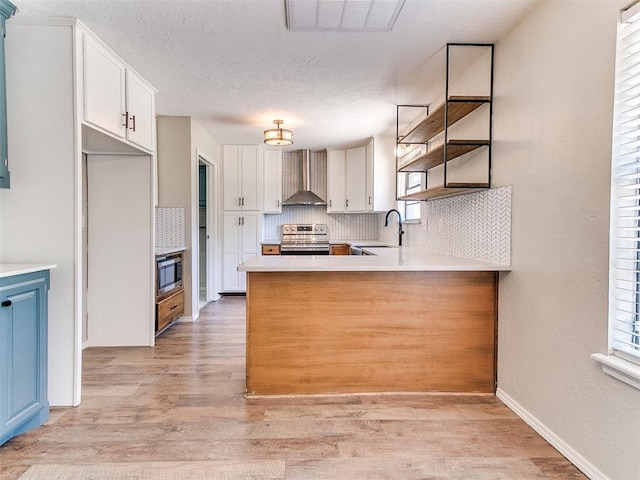 1400 Brookhaven Dr, Edmond, OK 73034 - kitchen with appliances with stainless steel finishes, a sink, decorative backsplash, light wood finished floors, and wall chimney range hood