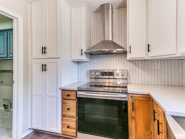 1400 Brookhaven Dr, Edmond, OK 73034 - kitchen featuring wall chimney exhaust hood, stainless steel range with electric cooktop, white cabinetry, backsplash, and light countertops