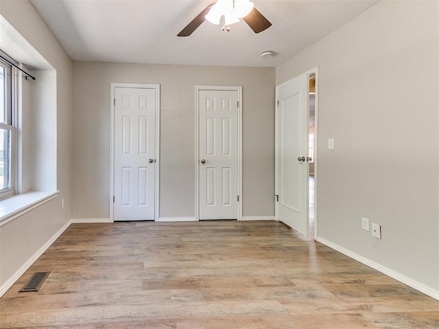 1400 Brookhaven Dr, Edmond, OK 73034 - unfurnished bedroom featuring multiple windows, light wood-style floors, baseboards, and a ceiling fan