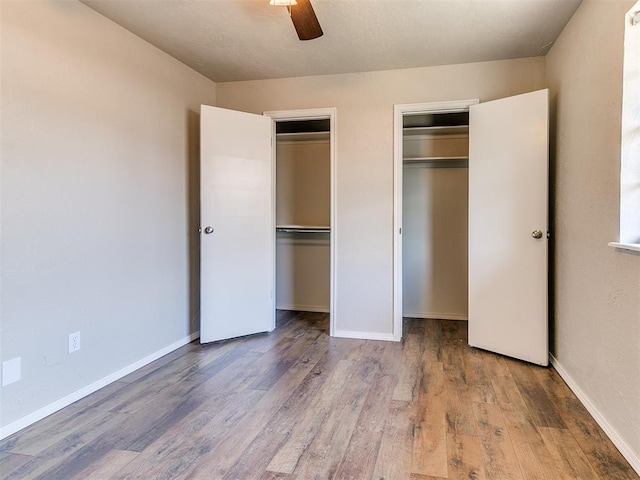 1400 Brookhaven Dr, Edmond, OK 73034 - unfurnished bedroom featuring wood finished floors, multiple closets, baseboards, and a ceiling fan