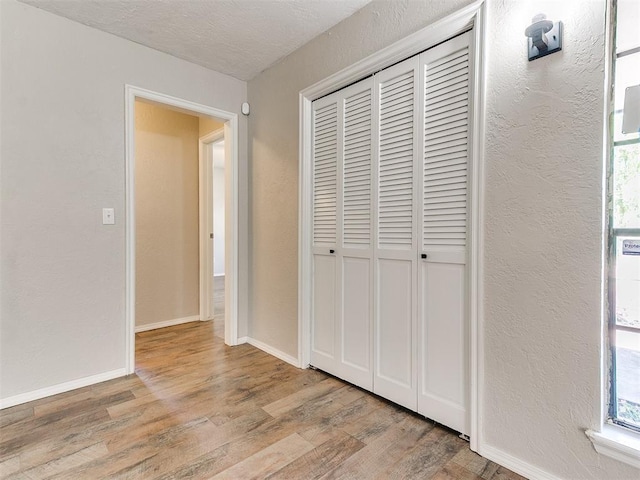1400 Brookhaven Dr, Edmond, OK 73034 - unfurnished bedroom featuring wood finished floors, a closet, baseboards, multiple windows, and a textured wall