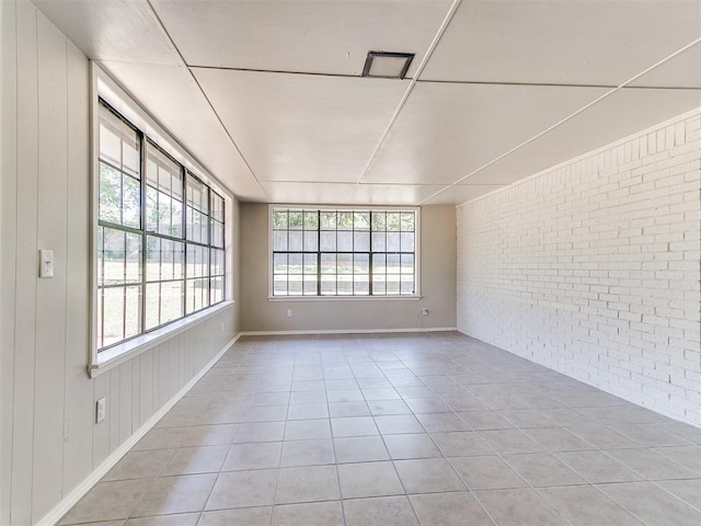 1400 Brookhaven Dr, Edmond, OK 73034 - empty room with brick wall and light tile patterned floors