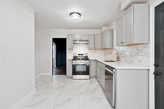 2321 NW 25th St, Oklahoma City, OK 73107 - kitchen featuring appliances with stainless steel finishes, a sink, under cabinet range hood, gray cabinetry, and baseboards