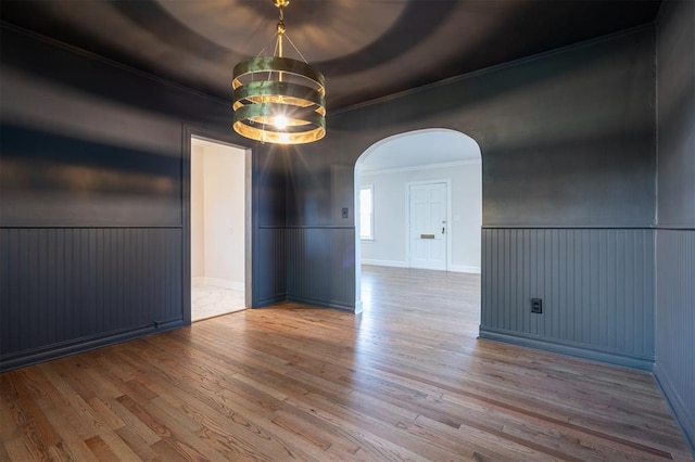 2321 NW 25th St, Oklahoma City, OK 73107 - empty room featuring crown molding, arched walkways, wood finished floors, a chandelier, and a wainscoted wall