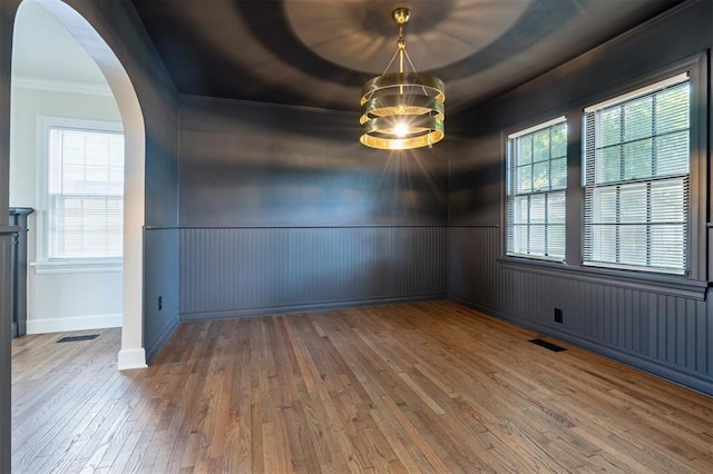 2321 NW 25th St, Oklahoma City, OK 73107 - unfurnished room with hardwood / wood-style flooring, ornamental molding, arched walkways, a wainscoted wall, and a chandelier