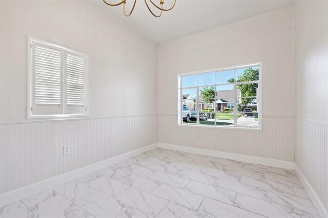 2321 NW 25th St, Oklahoma City, OK 73107 - unfurnished room with marble finish flooring, a chandelier, wainscoting, and baseboards